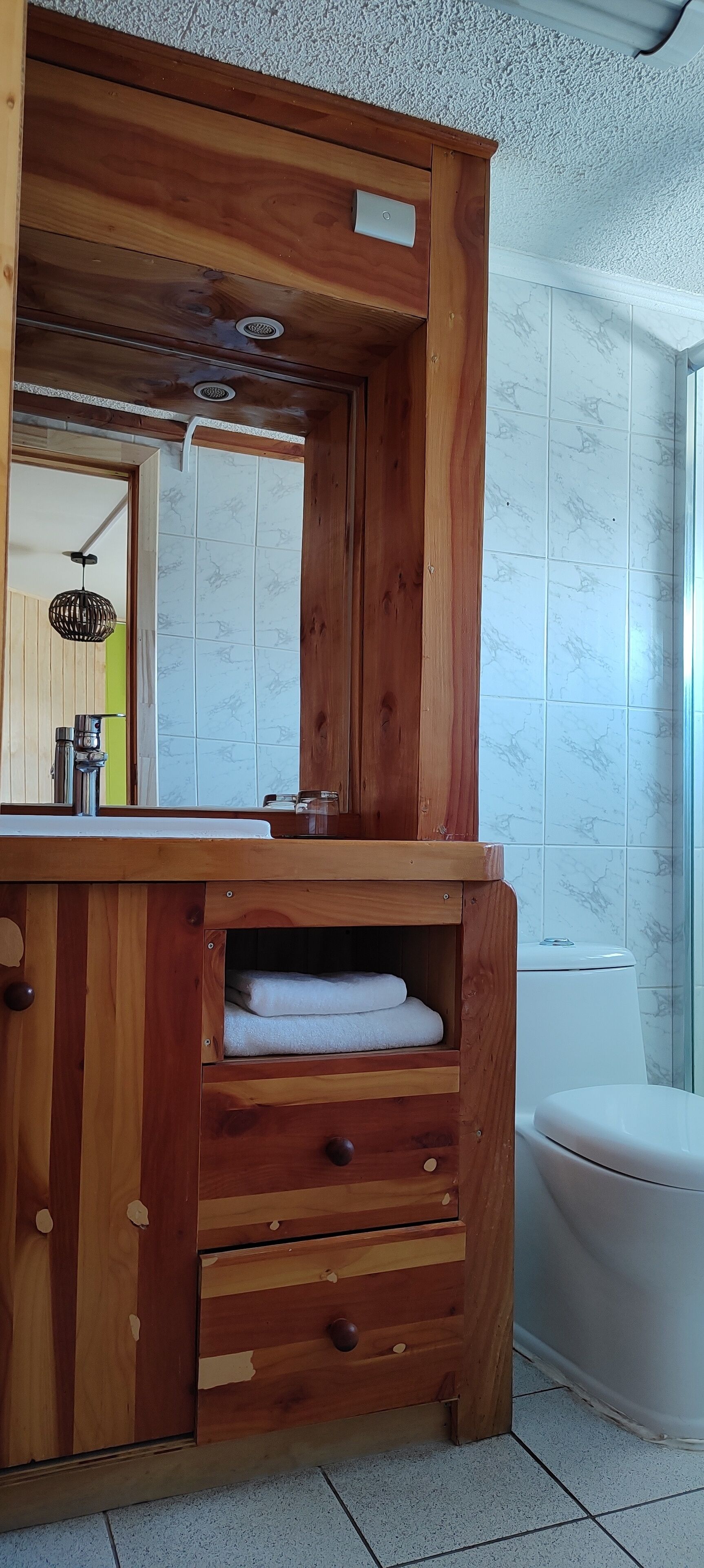 A wooden vanity with a mirror, a sink, and a towel shelf.