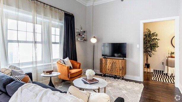Ett modernt vardagsrum med en soffa, fåtölj, soffbord, TV och en bokhylla.