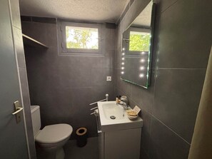 Un bany petit i funcional amb vàter, rentapla i mirall, i una petita finestra.