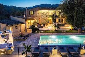 Uma casa de pedra com piscina, área de estar ao ar livre e jardim.