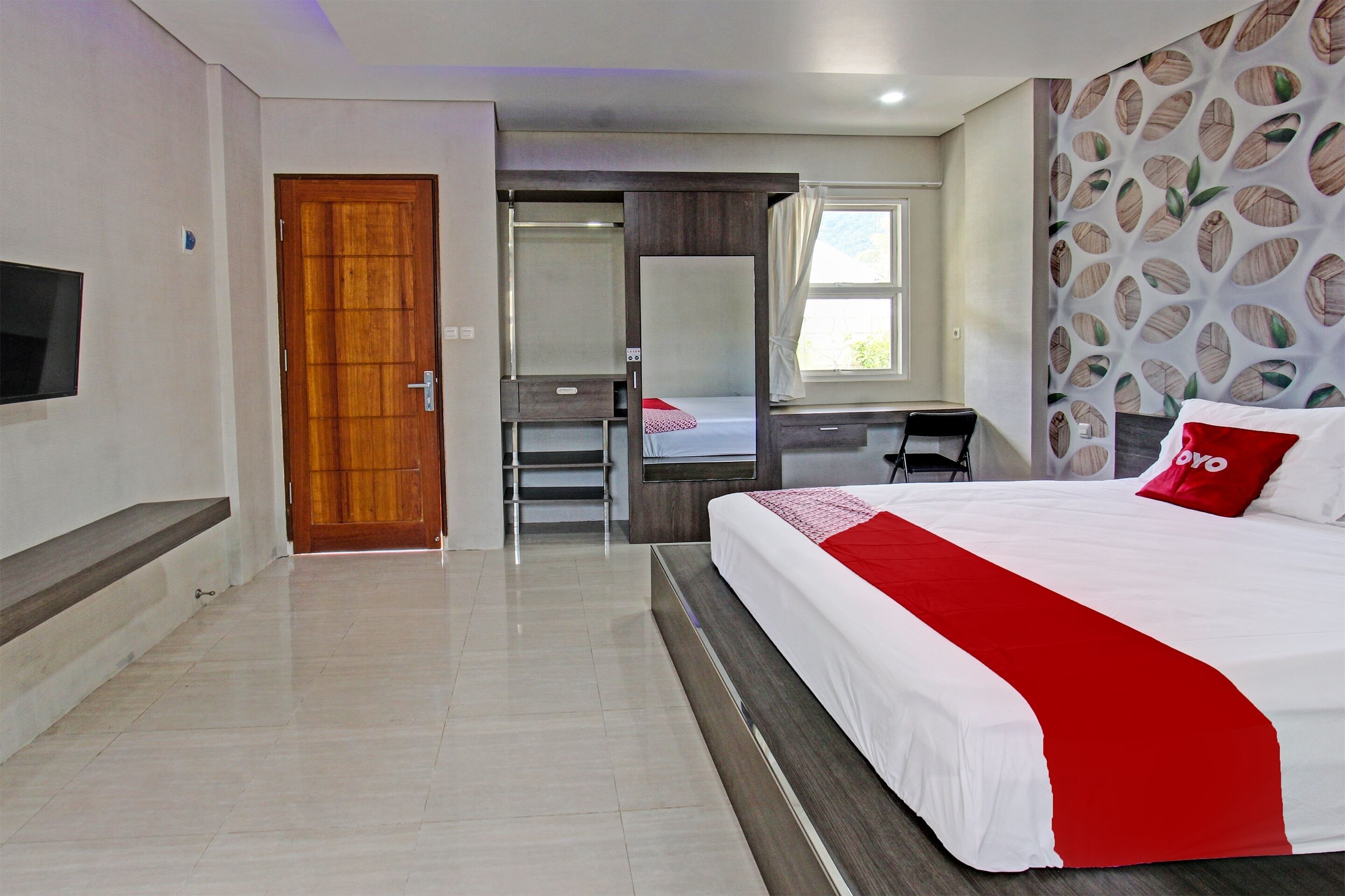 A hotel room with a bed, a desk, a wardrobe, and a television.