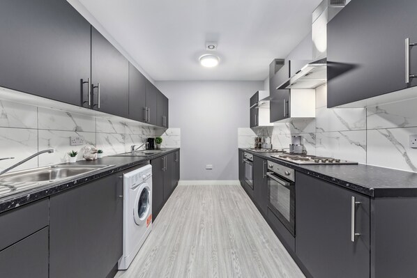 Enjoy cooking in this well-equipped kitchen with a washing machine, large sink, and stove.