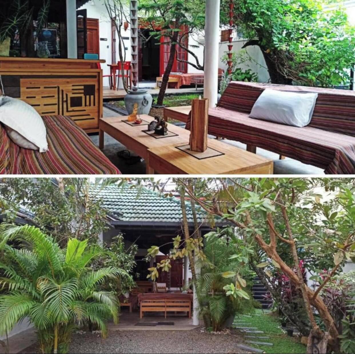 Un banc en bois traditionnel avec un coussin, une table en bois ornée d’une statue et un banc rouge avec un coussin blanc.
