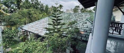 A covered outdoor area with a metal roof, surrounded by lush greenery and trees.