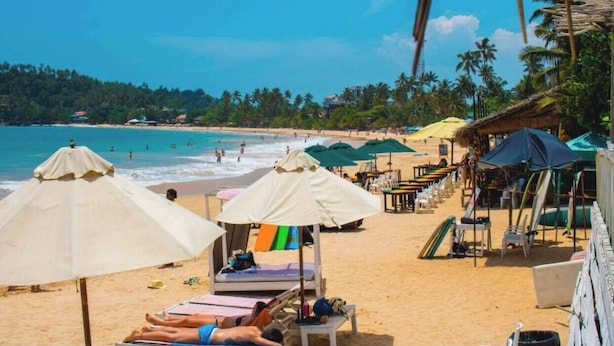 Une plage avec des transats, des parasols et des chaises de plage.