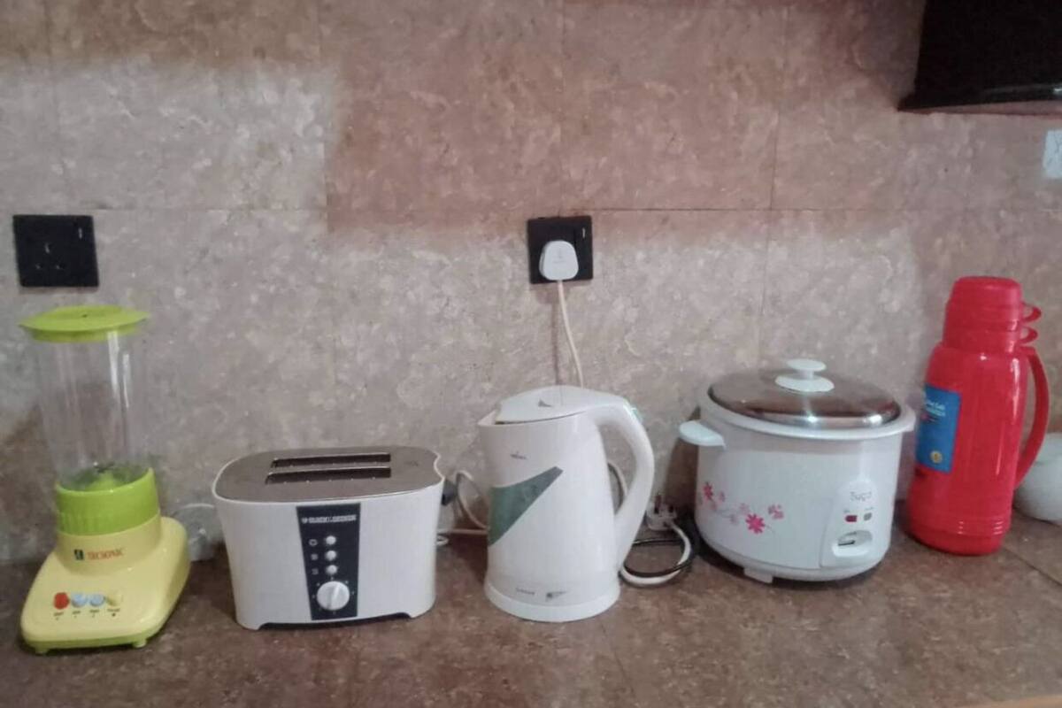 Un plan de travail de cuisine avec un mixeur, un grille-pain, une bouilloire, une mijoteuse et une bouteille d’eau rouge.