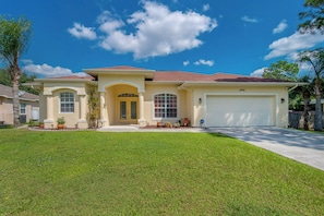 A two-story house with a garage, a well-maintained lawn, and a clear blue sky.