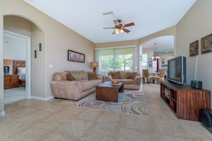 A spacious living room with two sofas, a coffee table, and a television on a wooden stand.