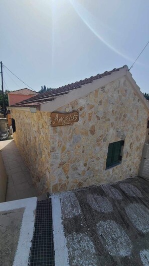 A stone building with a tiled roof and a sign that reads "Angelo's."