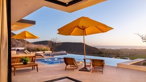 A poolside area with two wooden chairs, a table, and two yellow umbrellas. - Villa Damiana Adults Only (El Pescadero)