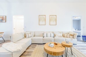 Un saló modern amb un sofà modular, dues taules de centre de fusta i una catifa amb dibuixos.