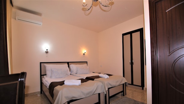 Une chambre avec deux lits, un lustre, un climatiseur et une porte.