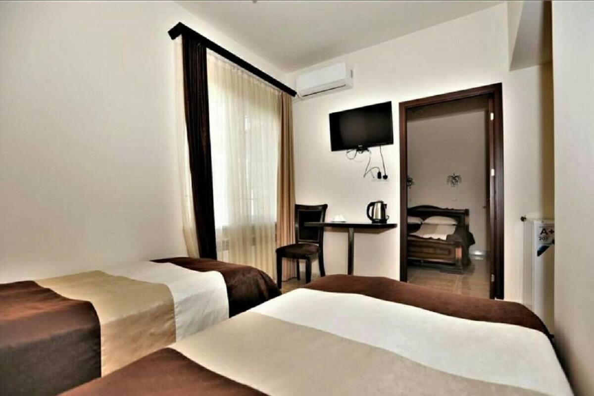 Ein Hotelzimmer mit zwei Betten, einem Fernseher, einem Schreibtisch und einem Stuhl.