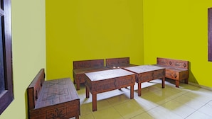 A room with a yellow wall, a wooden table with a geometric pattern, and a matching wooden bench. - OYO 91583 D’cost Green Syariah (Sidoarjo)