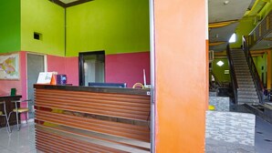 A reception area with a wooden counter, a map on the wall, and a staircase in the background. - OYO 91583 D’cost Green Syariah (Sidoarjo)