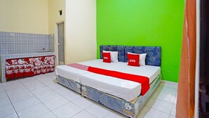 A bedroom with a bed, a bench, and a green wall. - OYO 91583 D’cost Green Syariah (Sidoarjo)