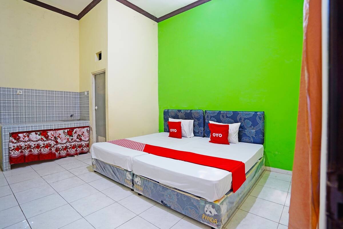 Un dormitorio con cama, un banco y una pared verde.