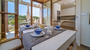 Un comedor con una mesa dispuesta para cuatro, una silla de mimbre y vistas al exterior.
