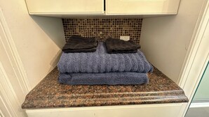 Un bany amb taulell de granat, un lavabo i una barra de tovalloles amb tovalloles plegades.