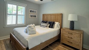 Quarto com cama de madeira, mesa de cabeceira, ventoinha no teto e janela com persianas.