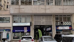 A multi-story building with several ground-level shops, including a pharmacy and a bank.