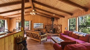 Un interior de madera con chimenea, un sofá, un televisor y un comedor.