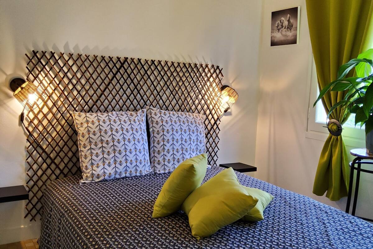 A bed with patterned bedding, a headboard with a lattice design, and two wall-mounted lamps.