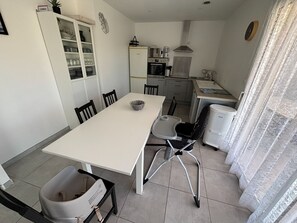 A compact kitchen with a dining area, including a table, chairs, and a small refrigerator.