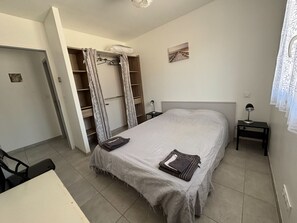 Une chambre à coucher comprenant un lit, un bureau, une chaise, une armoire et une table de chevet.