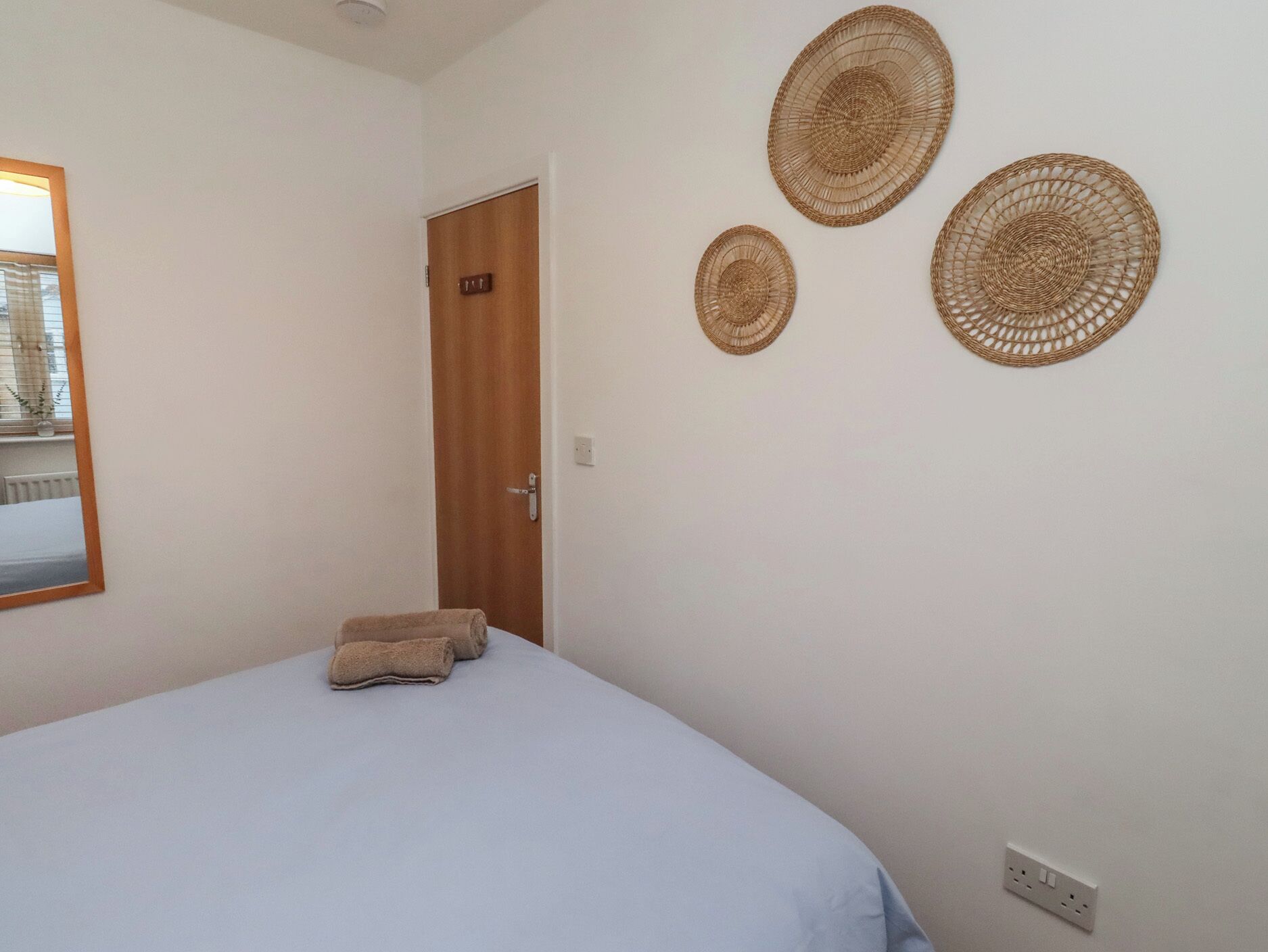 Une chambre à coucher avec un lit, une porte et trois sets de table en tissu tressé, accrochés au mur.