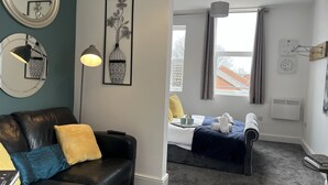 Una habitación moderna con un sofá de cuero negro, un espejo grande y una cama con vistas al exterior.