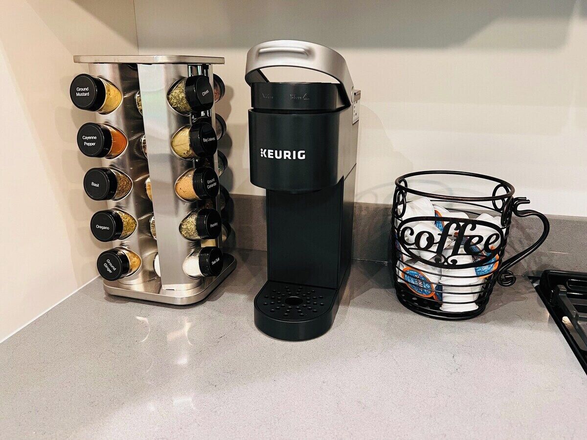 A Keurig coffee maker, a spice rack, and a coffee mug on a countertop.