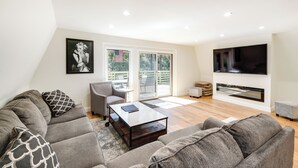 A modern living room with a grey sofa, a coffee table, and a flat-screen TV mounted on the wall. - Modern Pine Mountain Club Cabin w/ Community Pool! (Pine Mountain Club)