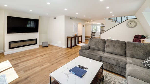 A modern living room with a large flat-screen TV, a gray sofa, and a white coffee table. - Modern Pine Mountain Club Cabin w/ Community Pool! (Pine Mountain Club)