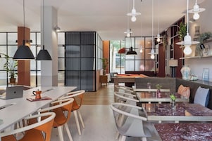Una cocina moderna con comedor, que incluye una mesa de mármol, sillas e iluminación colgante.