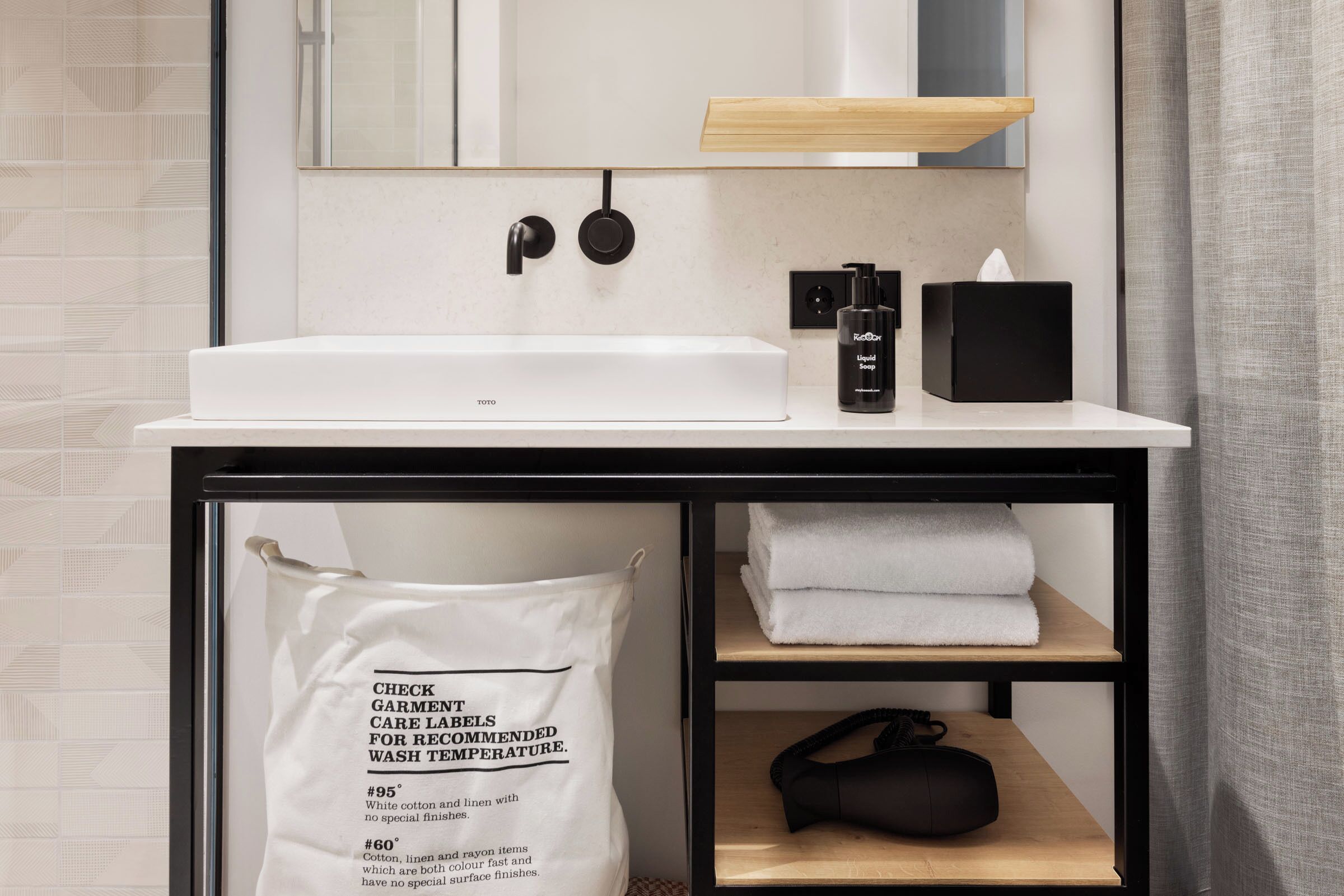 A modern bathroom with a white sink, black faucet, and a towel rack.