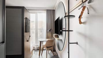 A compact hotel room with a dining area, a TV mounted on the wall, and a guitar hanging on the wall.