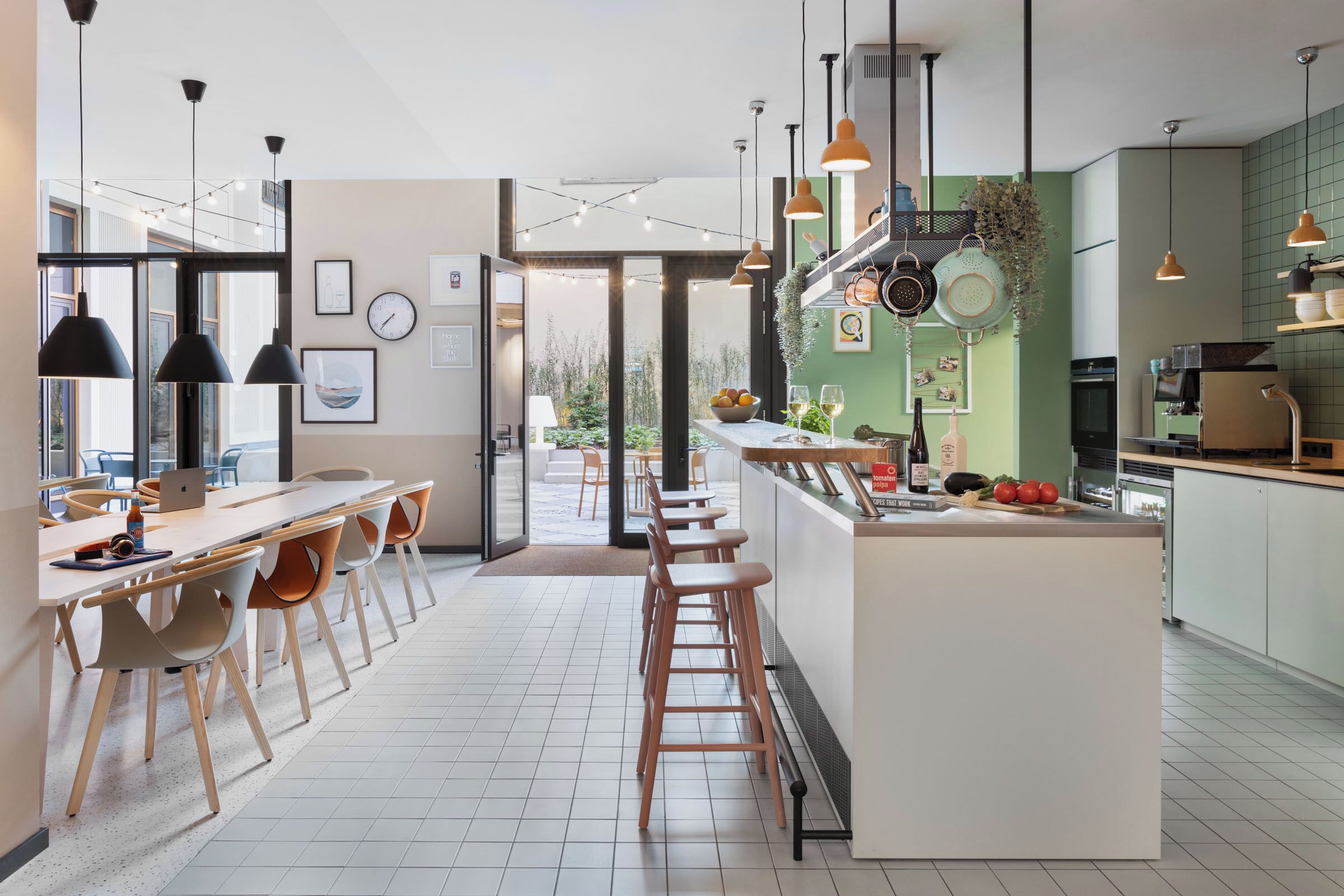 A modern kitchen with a central island, bar stools, pendant lighting, and a view to the outdoors.