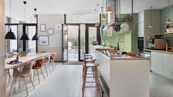 A modern kitchen with a central island, bar stools, pendant lighting, and a view to the outdoors.