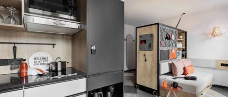 A compact kitchen with modern appliances, a dining area with a sofa, and a small table.