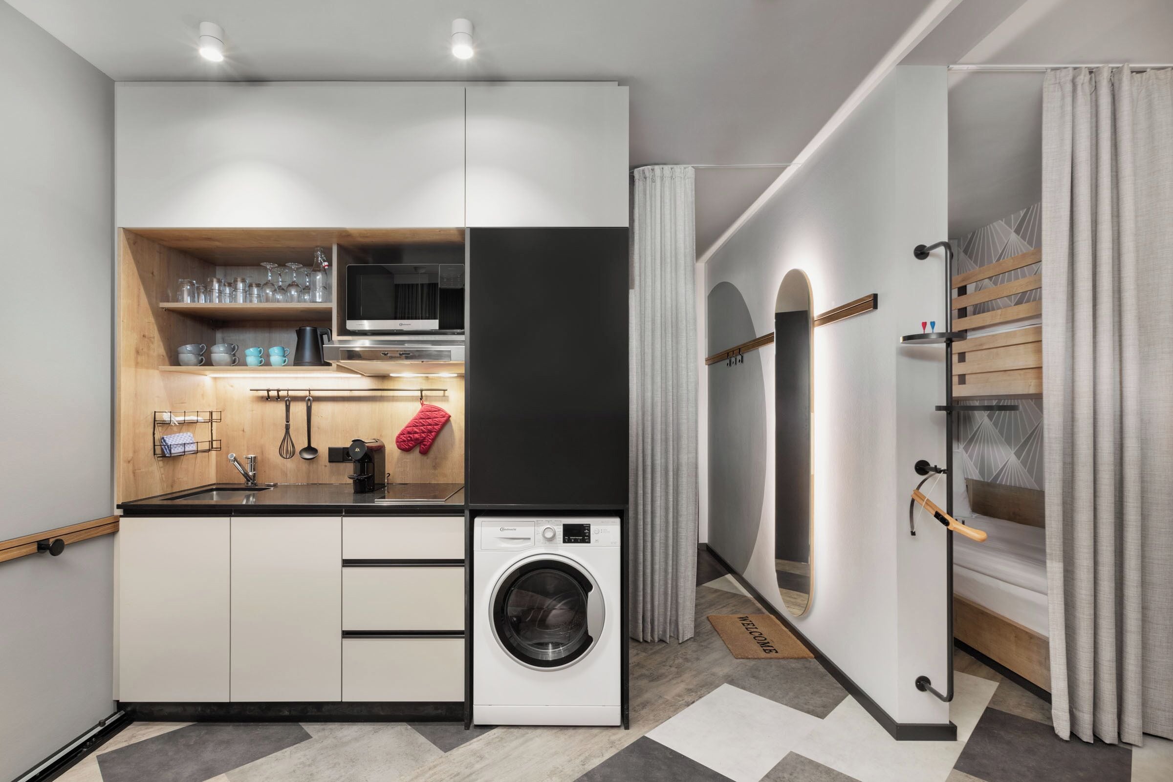 A compact kitchen with a built-in washing machine, a microwave, and a sink.