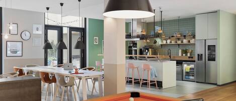 Una sala moderna con mesa de billar, comedor, cocina y vistas al exterior.
