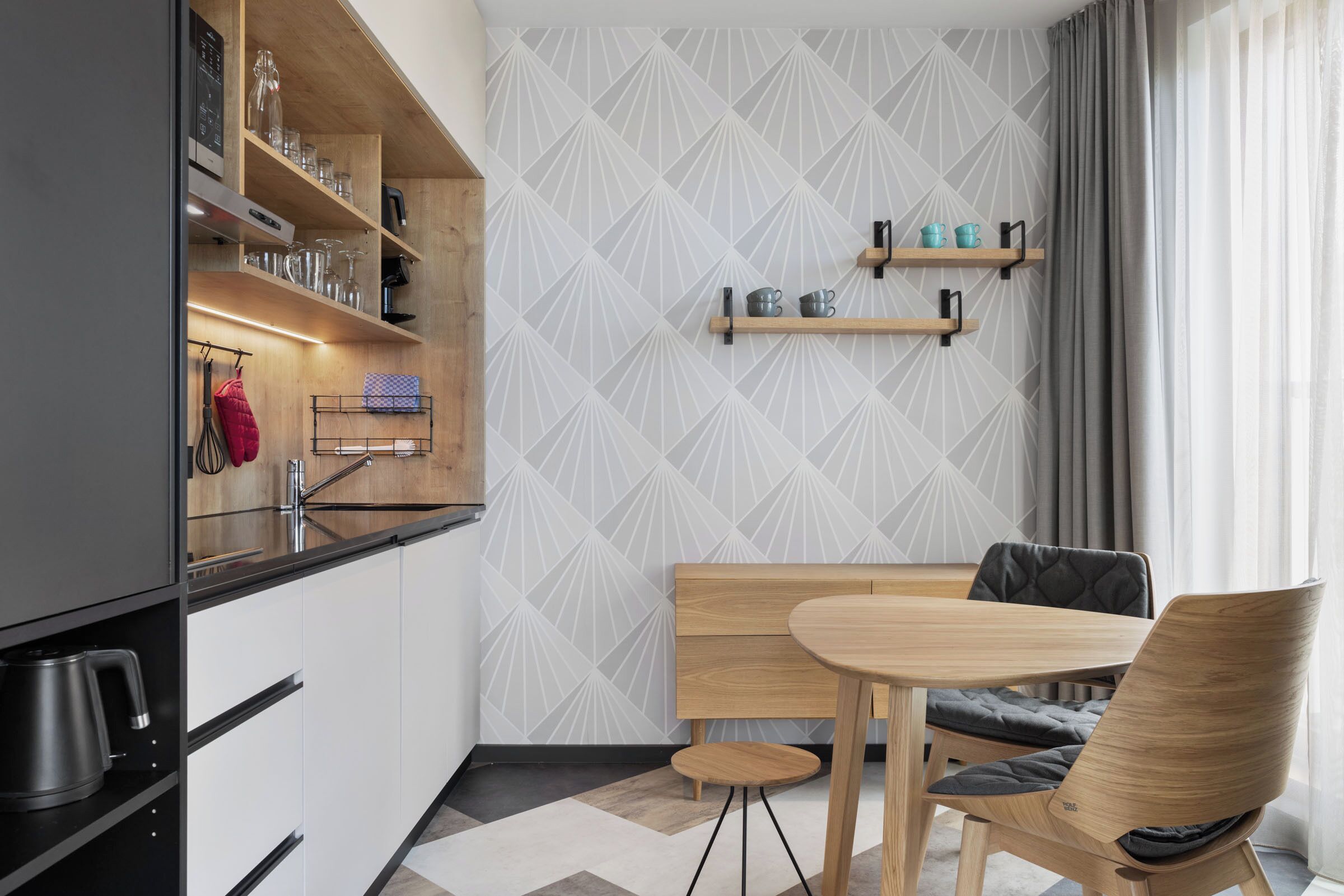 Una cocina moderna con armarios de madera, estufa integrada y comedor con mesa y sillas de madera.