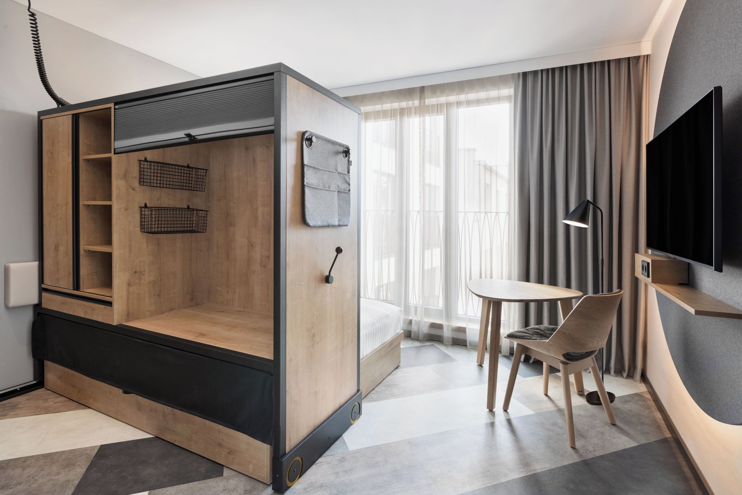 Une chambre d’hôtel moderne équipée d’un lit convertible, d’une petite table et d’un téléviseur.