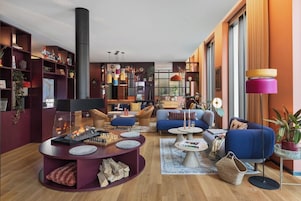 Una sala de estar moderna con chimenea, sofás azules, una mesita de centro y una estantería llena de objetos diversos.