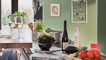 A kitchen counter with two wine glasses, a bowl of salad, a bottle of oil, a book titled 'Recipes That Work,' and fresh tomatoes.