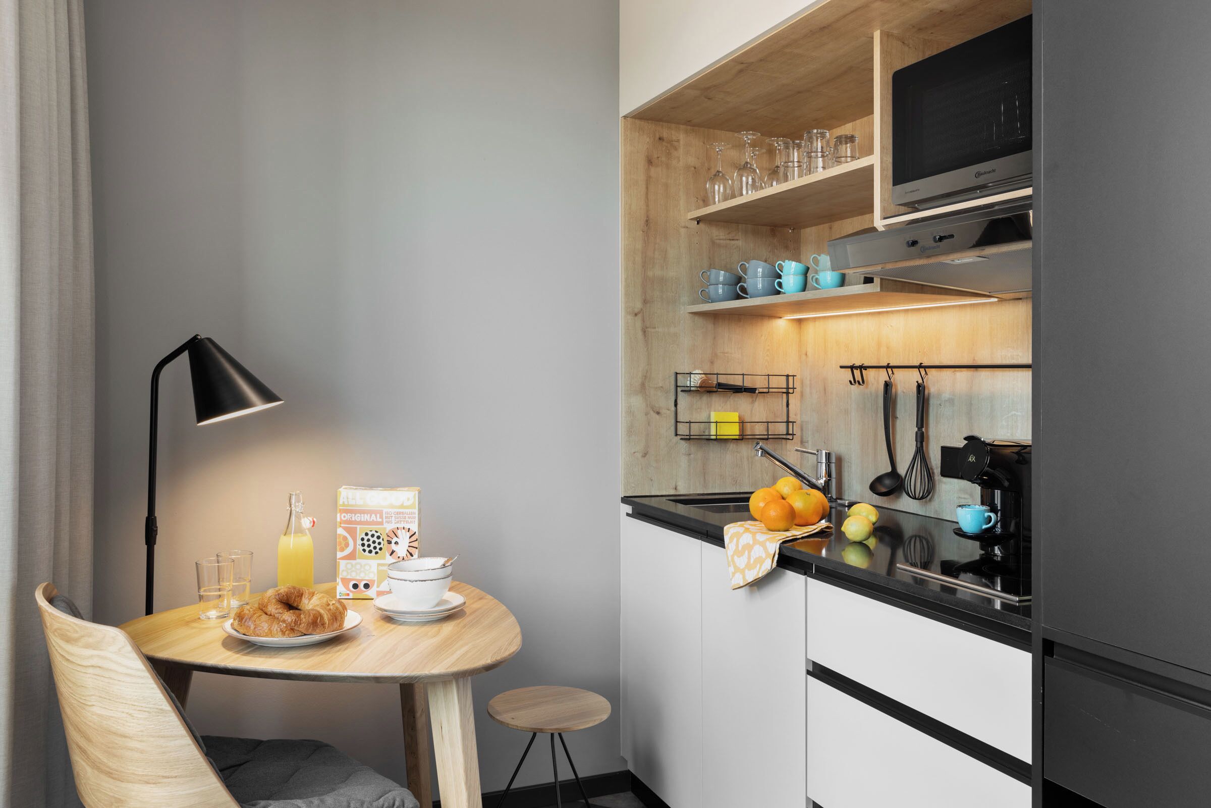 Eine kompakte Küche mit Essbereich, inklusive Tisch mit Frühstücksangebot, einer Mikrowelle und einer Kaffeemaschine.