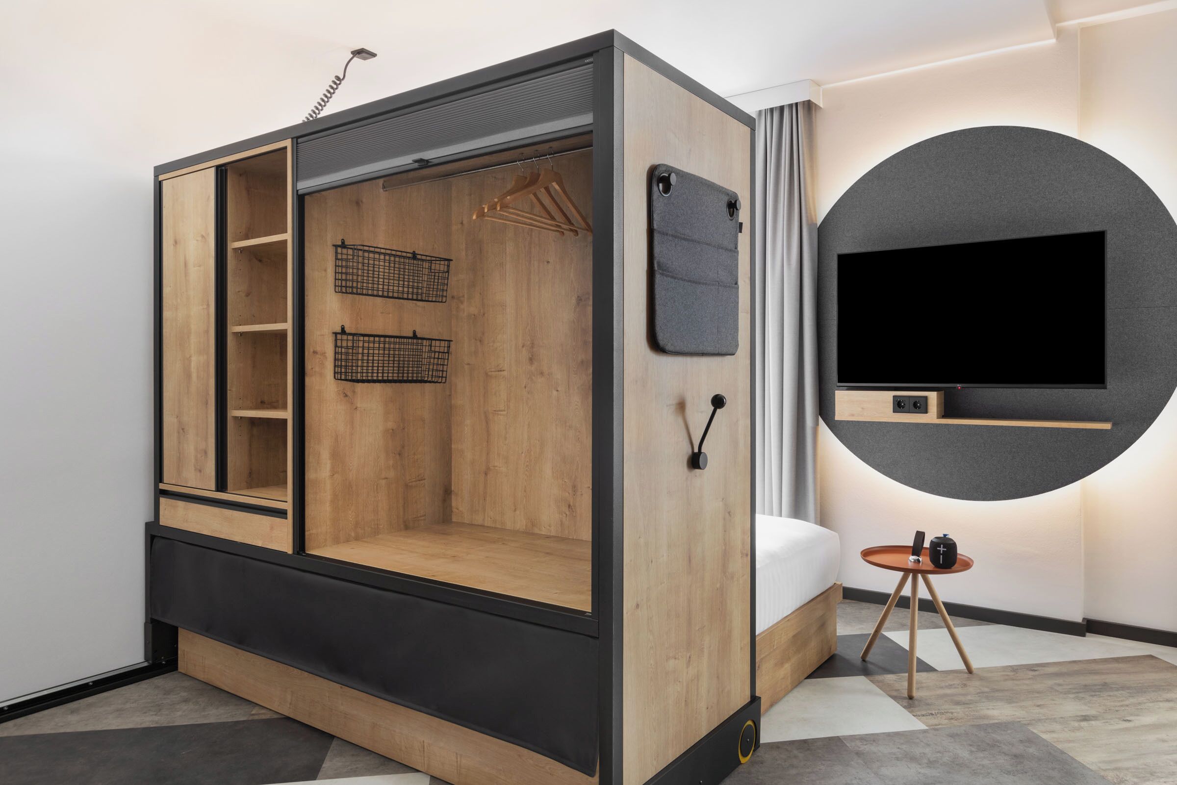 A modern room with a built-in bed, a TV, and a small table with a lamp.