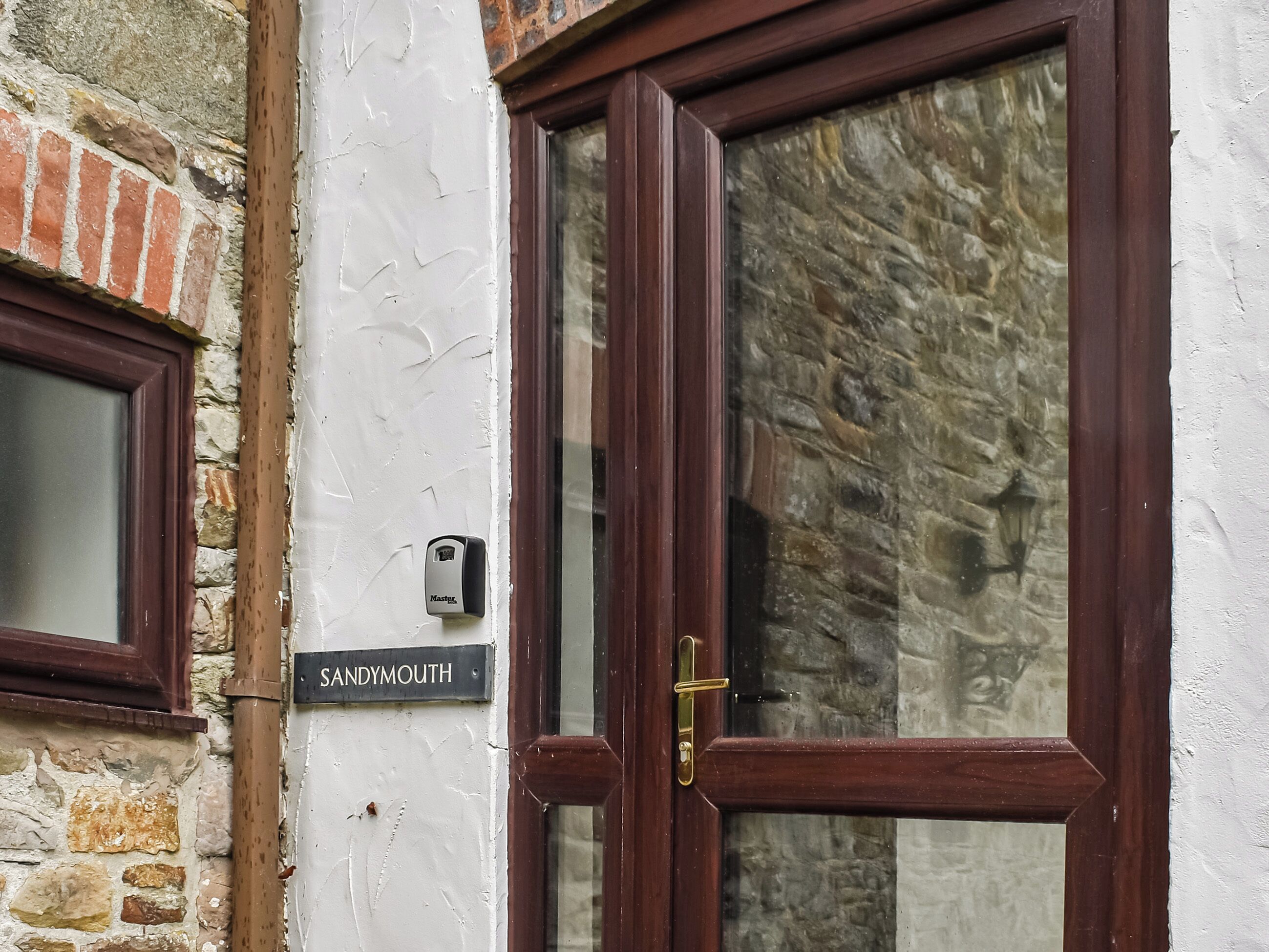 A wooden door with a brass handle, a window with a white frame, and a sign reading "SANDYMOUTH".