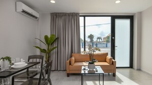 Ein modernes Wohnzimmer mit einer Couch, einem Esstisch, Stühlen und einer Topfpflanze.